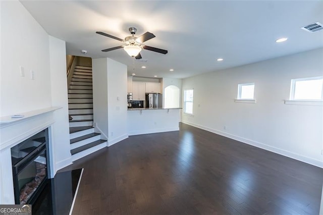 unfurnished living room featuring ceiling fan and dark hardwood / wood-style flooring