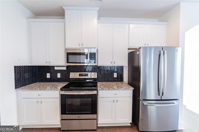 kitchen with stainless steel appliances, white cabinetry, and tasteful backsplash