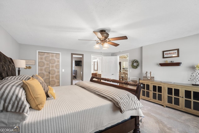 carpeted bedroom featuring ensuite bathroom, a textured ceiling, and ceiling fan