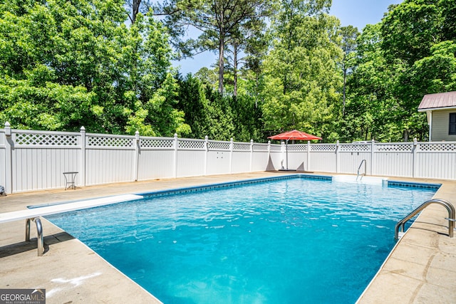 view of swimming pool with a diving board