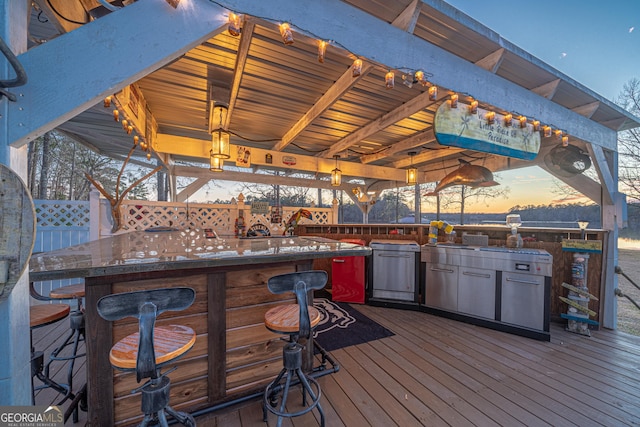 deck at dusk featuring exterior bar