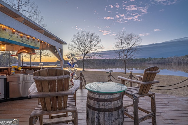 deck at dusk featuring a water view