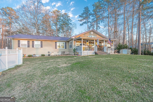 view of front of property featuring covered porch, a front yard, and a shed