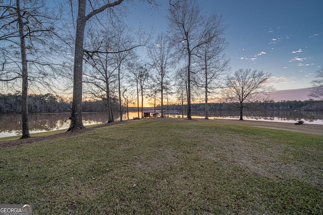 yard at dusk featuring a water view