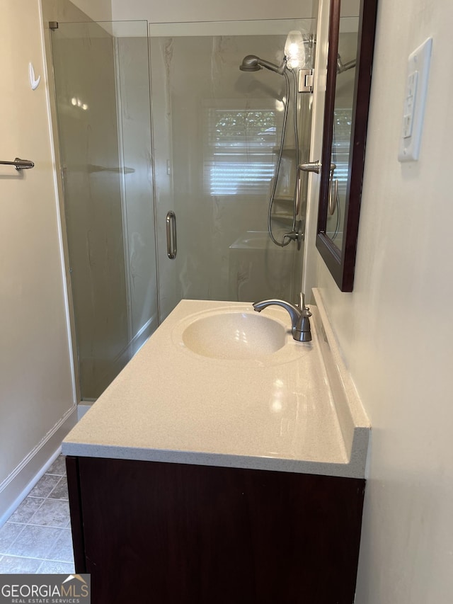 bathroom featuring vanity, a shower with shower door, and tile patterned floors