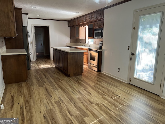 kitchen featuring appliances with stainless steel finishes, light hardwood / wood-style floors, crown molding, and a center island