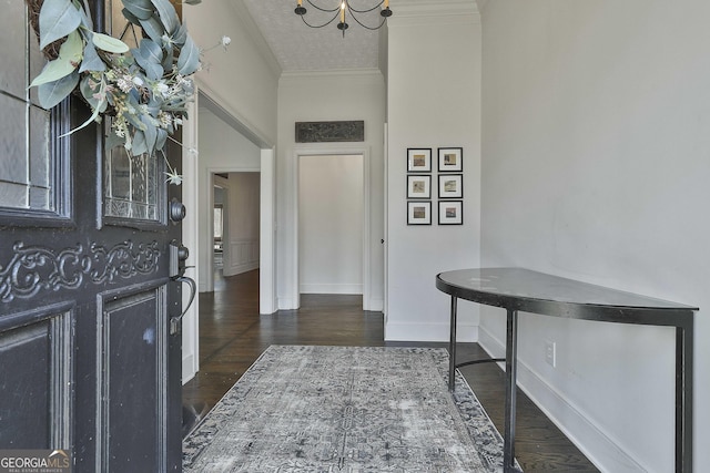 foyer entrance with a textured ceiling, ornamental molding, dark hardwood / wood-style flooring, and an inviting chandelier