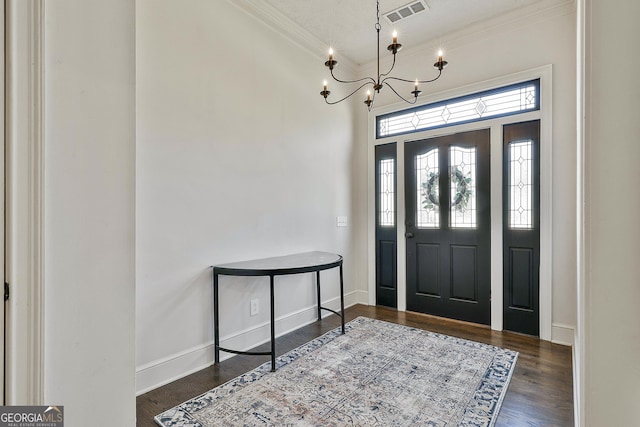 entryway with a notable chandelier, wood finished floors, visible vents, baseboards, and crown molding