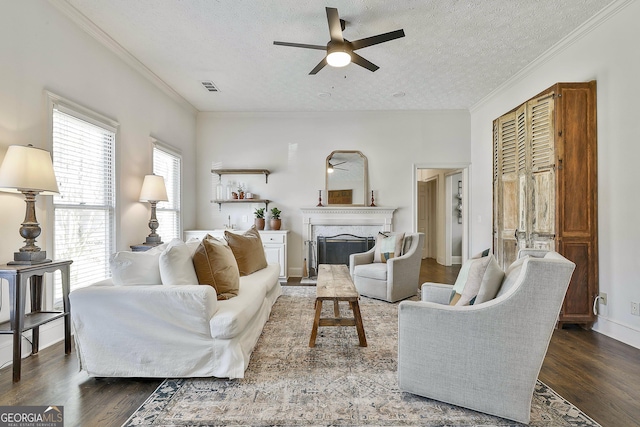 living area with a ceiling fan, wood finished floors, visible vents, and a high end fireplace