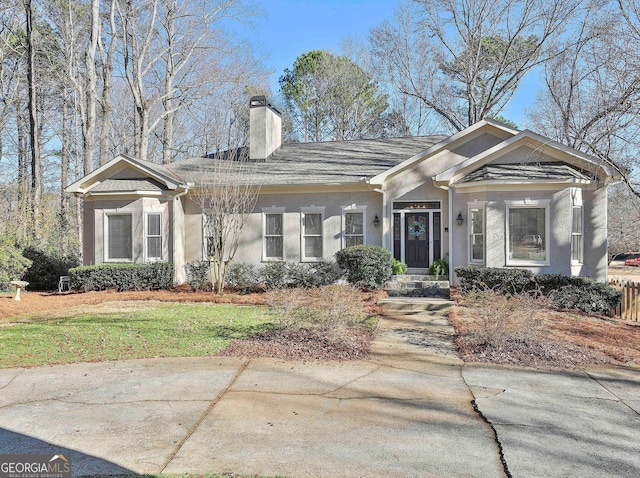 view of front of house with a front lawn, a chimney, and stucco siding