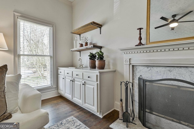 sitting room featuring dark wood-type flooring, a fireplace, baseboards, and a ceiling fan