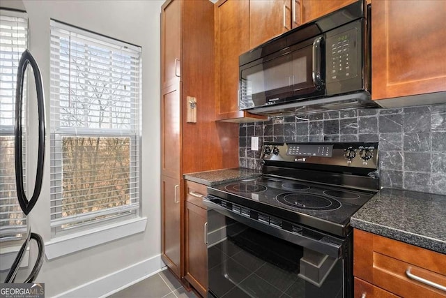 kitchen featuring tile patterned flooring, tasteful backsplash, black appliances, and dark stone counters