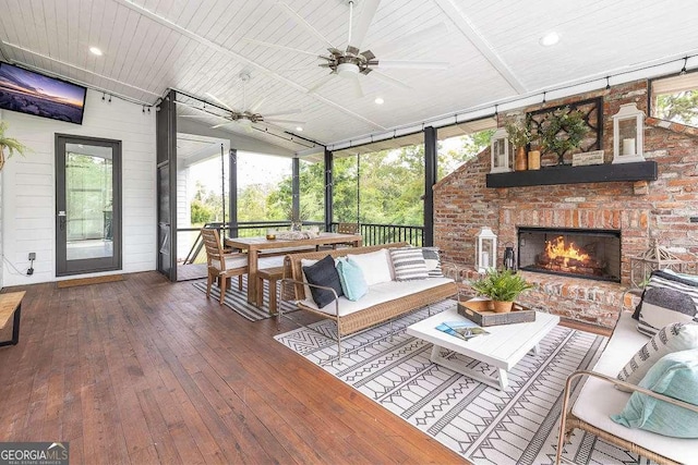 sunroom with an outdoor brick fireplace, wood ceiling, and ceiling fan