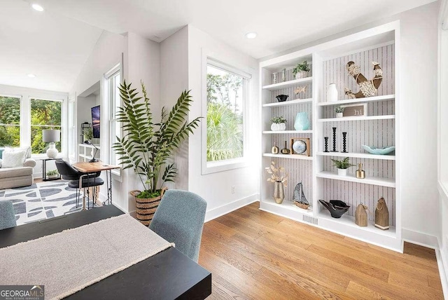 home office featuring a healthy amount of sunlight, built in shelves, baseboards, and wood finished floors