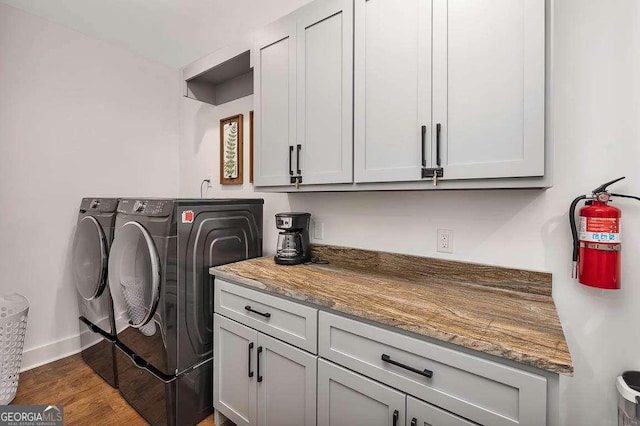 washroom with washer and clothes dryer, cabinets, and dark wood-type flooring