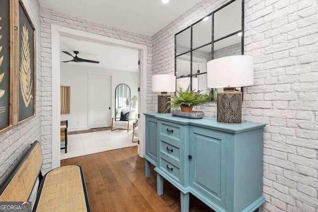 interior space with dark wood finished floors, brick wall, and ceiling fan