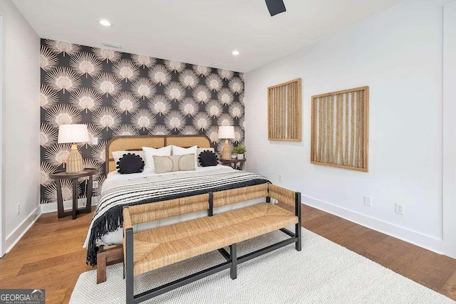 bedroom with recessed lighting, an accent wall, wood finished floors, baseboards, and wallpapered walls