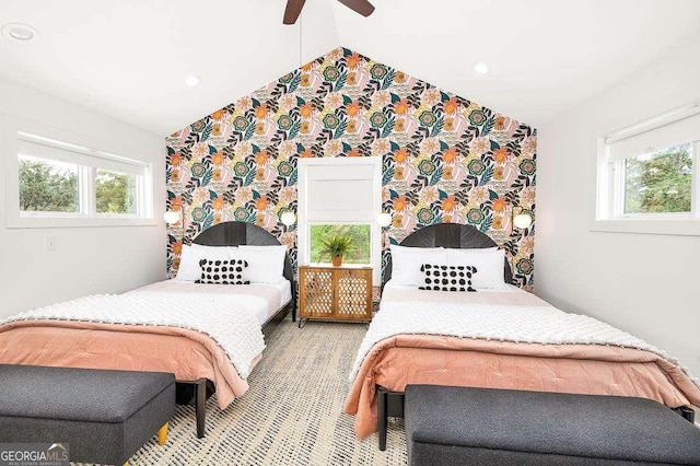 bedroom with a ceiling fan, lofted ceiling, multiple windows, and wallpapered walls