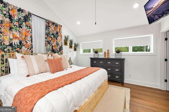 bedroom featuring hardwood / wood-style floors, vaulted ceiling, and multiple windows