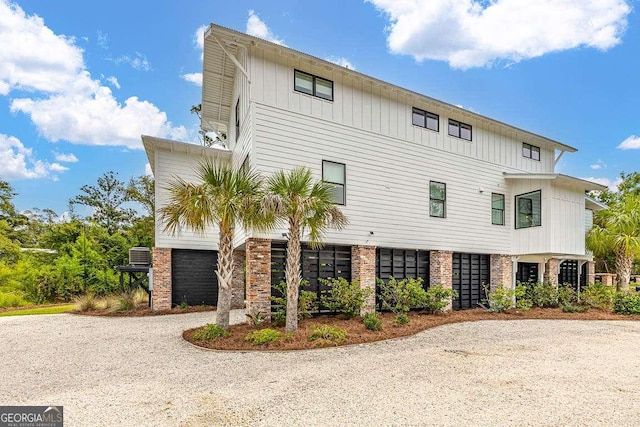 exterior space featuring cooling unit, brick siding, and driveway