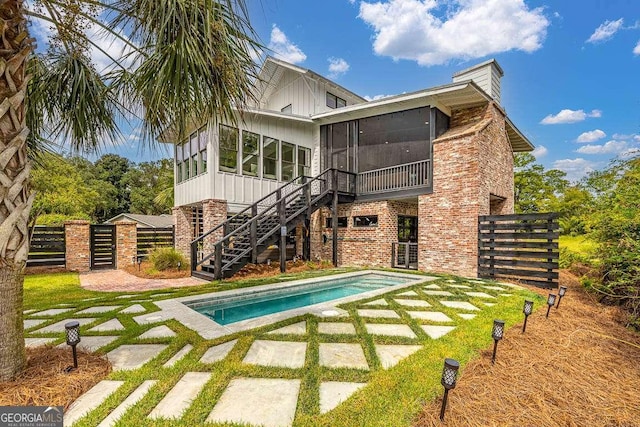 back of property with brick siding, fence, a sunroom, stairs, and an outdoor pool