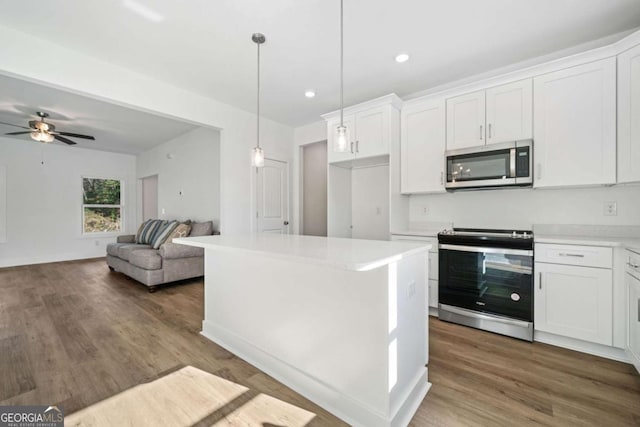 kitchen featuring pendant lighting, stainless steel appliances, a kitchen island, white cabinetry, and ceiling fan