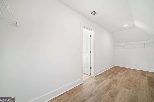 additional living space with light wood-type flooring and lofted ceiling