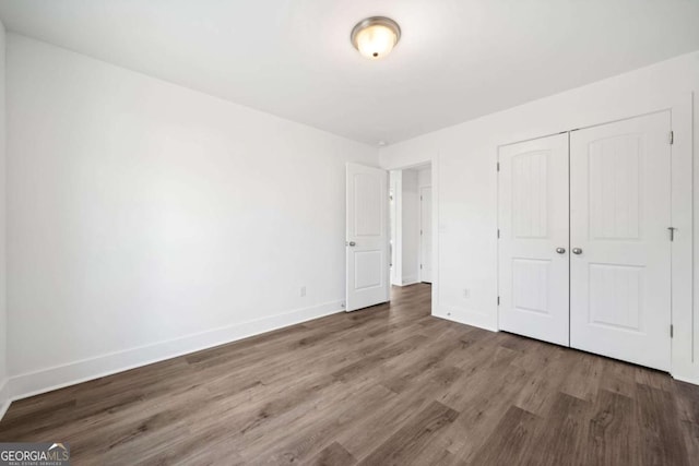 unfurnished bedroom featuring a closet and dark hardwood / wood-style flooring