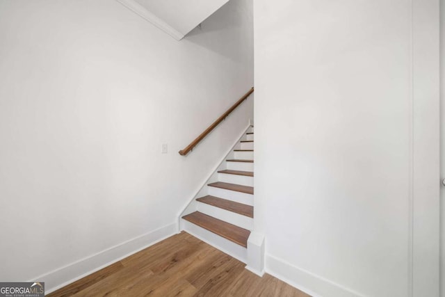 staircase with hardwood / wood-style flooring and crown molding