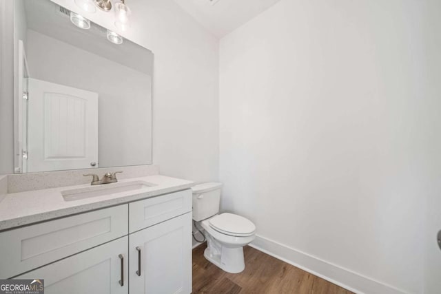 bathroom with toilet, hardwood / wood-style flooring, and vanity