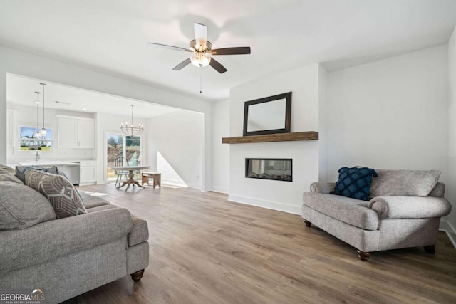 living room with ceiling fan with notable chandelier and hardwood / wood-style floors