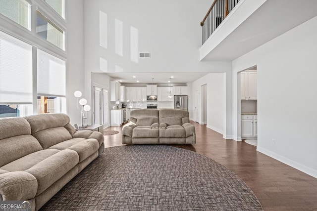 living room featuring dark wood-type flooring and a towering ceiling