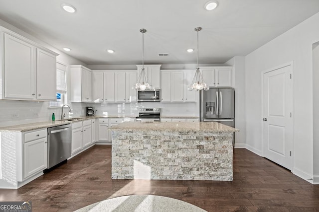 kitchen featuring appliances with stainless steel finishes, pendant lighting, dark hardwood / wood-style floors, a kitchen island, and white cabinets