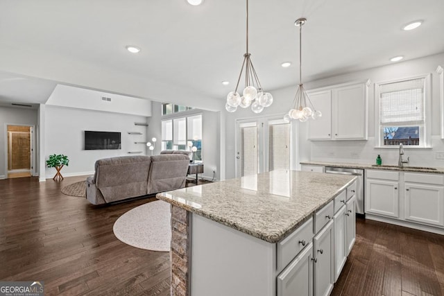 kitchen with pendant lighting, tasteful backsplash, a kitchen island, white cabinets, and sink