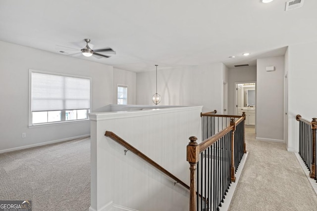 hall with a notable chandelier and light colored carpet