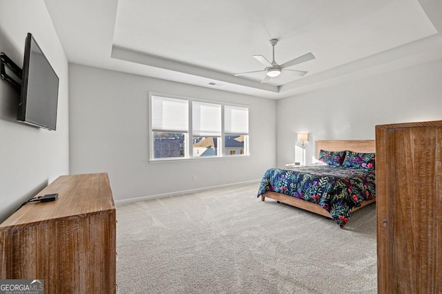 carpeted bedroom with ceiling fan and a tray ceiling