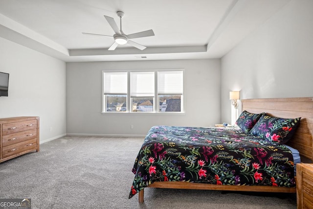 bedroom with carpet floors, ceiling fan, and a tray ceiling