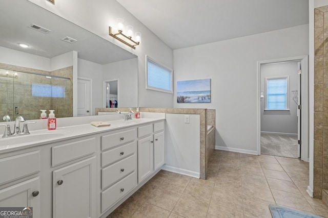 bathroom with a shower with door, tile patterned floors, and vanity