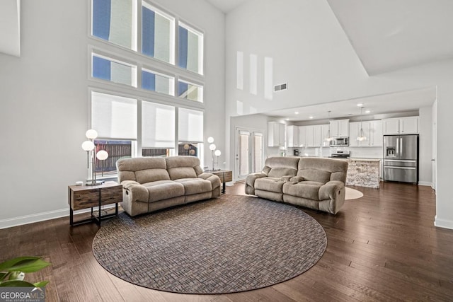 living room featuring a high ceiling and dark wood-type flooring