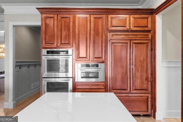 kitchen with paneled refrigerator, double oven, and crown molding