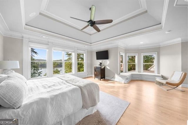 bedroom featuring ceiling fan, a tray ceiling, ornamental molding, and light hardwood / wood-style flooring