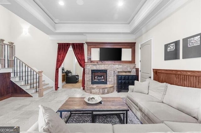 living room featuring a raised ceiling, a fireplace, and ornamental molding