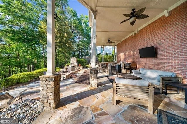 view of patio featuring ceiling fan and an outdoor living space with a fireplace