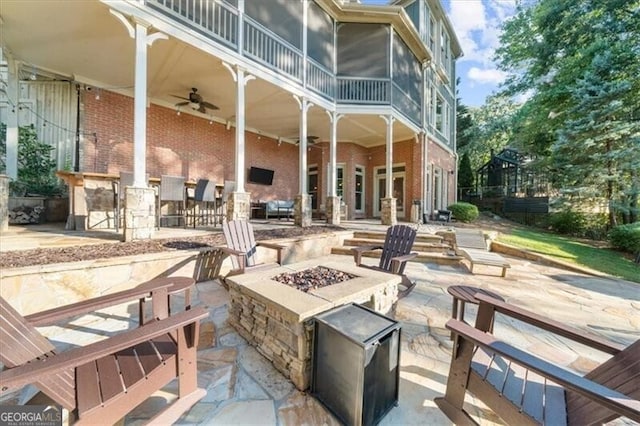 view of patio / terrace with ceiling fan, a fire pit, and a sunroom