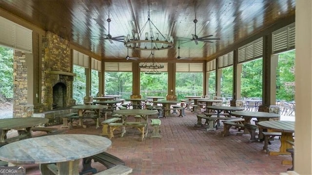 sunroom / solarium featuring ceiling fan and a stone fireplace