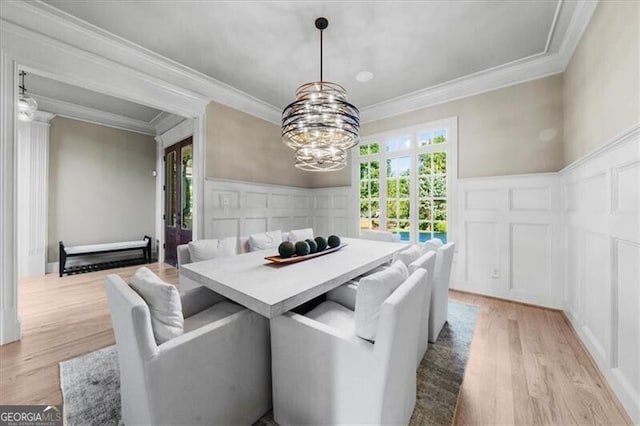 dining space featuring ornamental molding, light hardwood / wood-style flooring, a healthy amount of sunlight, and an inviting chandelier