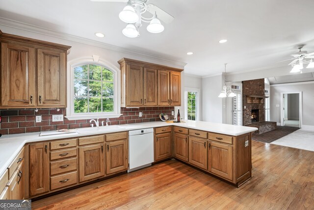 kitchen featuring dishwasher, decorative light fixtures, a fireplace, sink, and kitchen peninsula