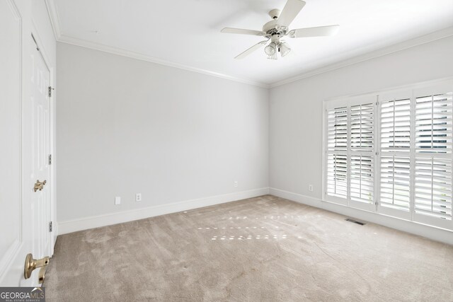 unfurnished room featuring ceiling fan, light colored carpet, and crown molding