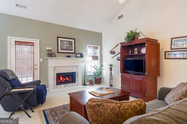 carpeted living room featuring a high end fireplace and lofted ceiling