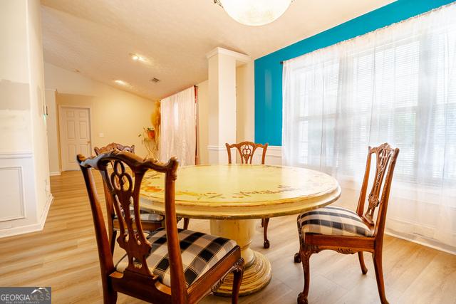 dining room featuring lofted ceiling and light hardwood / wood-style flooring